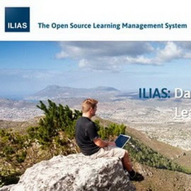 Mann mit Laptop auf Felsen, Blick auf Stadt und Berge im Hintergrund.